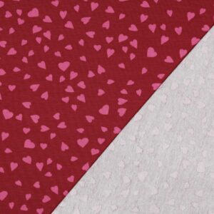 Tissu french terry rouge framboise avec motif de petits cœurs roses répartis sur toute la surface.